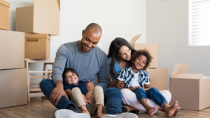 Family smiling and sitting by moving boxes
